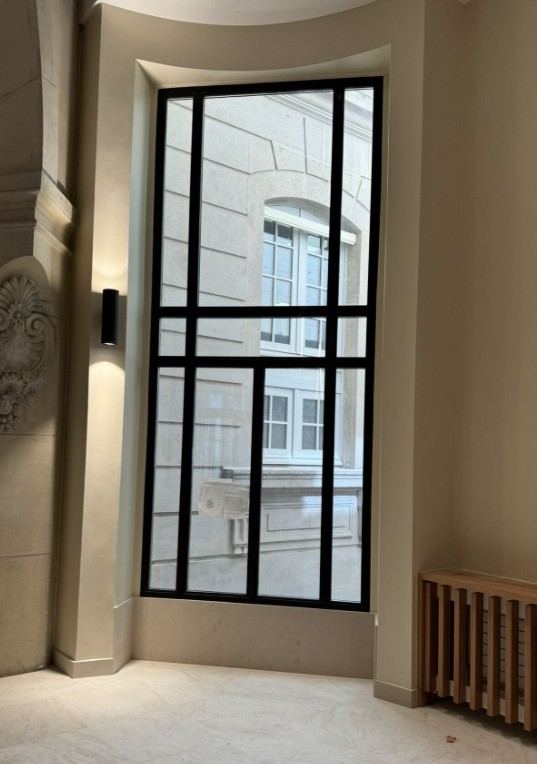Fenêtre en acier noir dans une embrasure en pierre